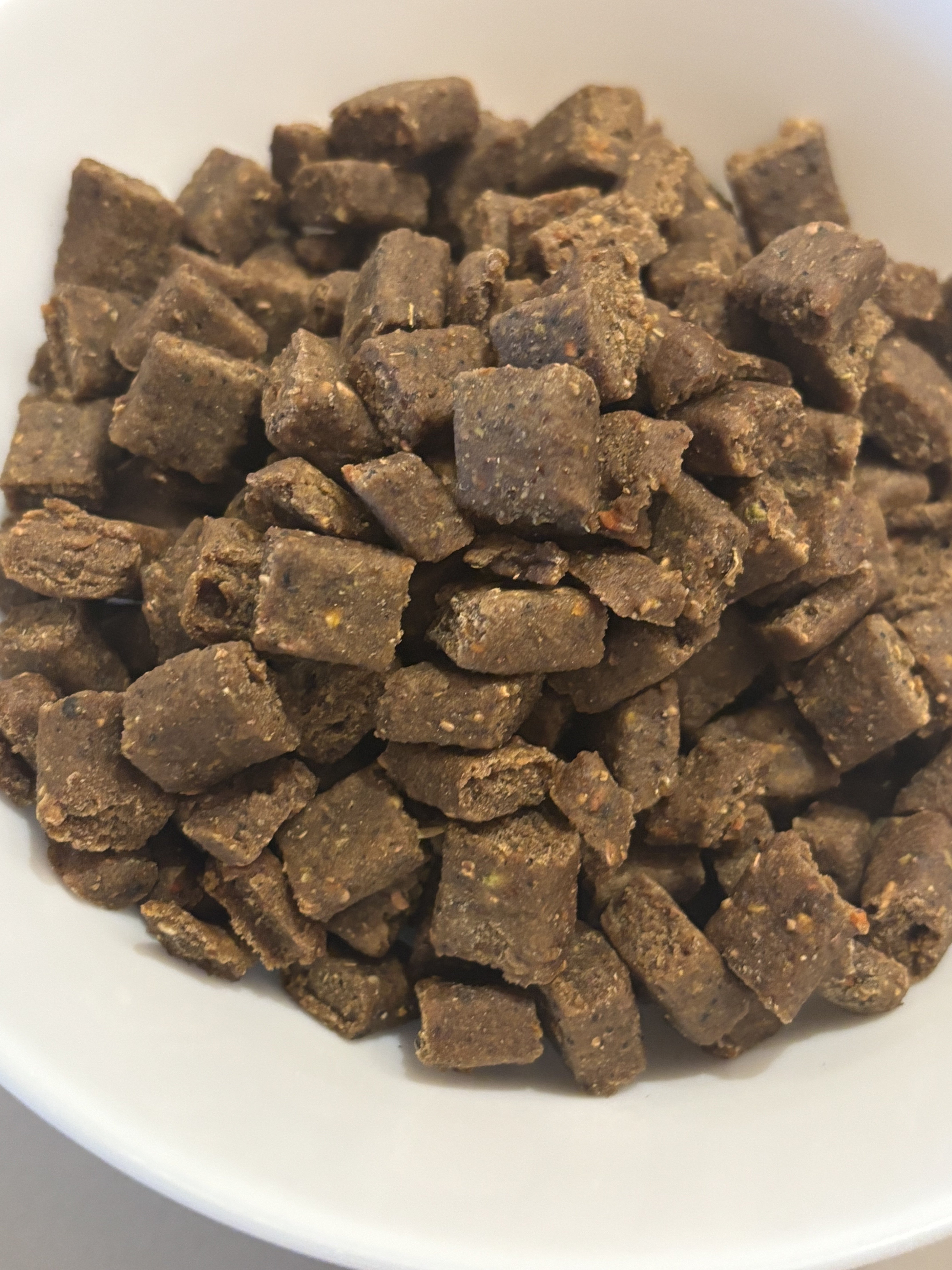 HenArt Airfusion™ Trockenfutter-Kibble auf natürlicher Holzoberfläche mit Erdtönen